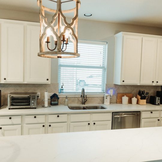 Bright and modern kitchen featuring white cabinetry, a stylish farmhouse sink, and rustic pendant lighting. Expertly renovated by professional contractors serving Houston, Spring, and Kingwood.