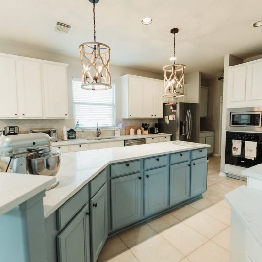 Bright and airy kitchen remodel featuring a large blue island, quartz countertops, and modern pendant lighting. Expertly renovated by a top-rated general contractor serving Katy, Pasadena, and the Greater Houston Area.